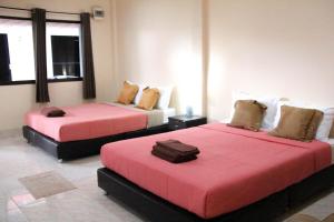 a room with two beds with red sheets at Sirikul Mansion in Nai Yang Beach