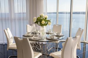 a dining table with white chairs and a vase of flowers at Just Stay Wales - Meridian Quay Penthouses in Swansea
