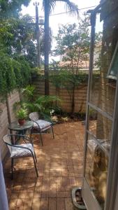 een terras met twee stoelen en een tafel en een glazen deur bij Love Joy Peace Cottage in Pretoria +1 foto