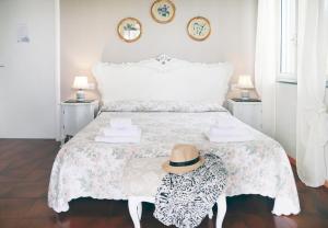 a white bedroom with a bed with a hat on it at Villa Ortensia in Aci Castello