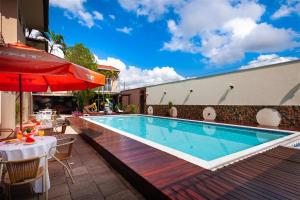 a swimming pool with a table and a red umbrella at Hotel 365 in Cuiabá
