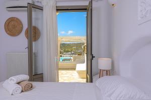 a bedroom with a bed and a view of the ocean at 9 Muses Villas Mykonos in Ornos