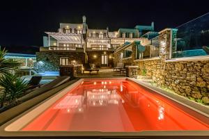 a swimming pool in front of a house at night at 9 Muses Villas Mykonos in Ornos