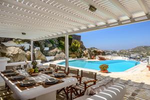 a patio with a table and chairs and a swimming pool at 9 Muses Villas Mykonos in Ornos