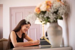 a woman sitting at a table with a vase of flowers at Le Cavendish in Cannes