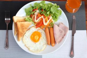um prato de comida de pequeno-almoço com um ovo e vegetais em Sirikul Mansion em Nai Yang Beach