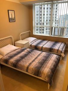 two beds in a room with a large window at Mississauga Furnished Apartments in Mississauga