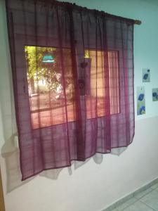 a window with pink curtains on a wall at Anemoxadi Apartments in Siviri