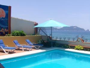 una piscina con 2 sillas y una sombrilla en La Paloma Oceanfront Retreat, en San Patricio Melaque