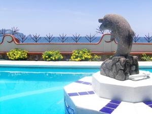 a statue of a dog sitting next to a swimming pool at La Paloma Oceanfront Retreat in San Patricio Melaque