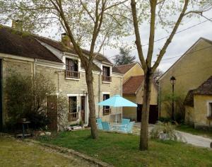 dom z niebieskim parasolem i krzesłami na dziedzińcu w obiekcie Charmante Maison à Recloses w mieście Recloses