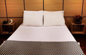 a large white bed with two pillows and two tables at Santa Maria Park Hotel in Garça