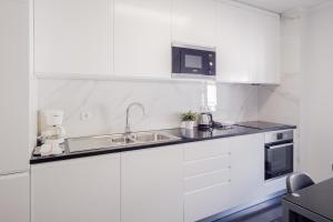 cocina blanca con fregadero y microondas en Music House 3 bedroom Apt w garage, en Oporto