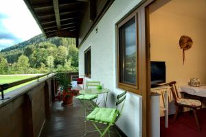 einen Balkon mit einem Tisch und Stühlen sowie einem TV in der Unterkunft Pension Forsthof in Maishofen