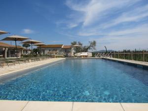 a large swimming pool with chairs and umbrellas at Agriturismo Sweet Cottage in Marina di Grosseto