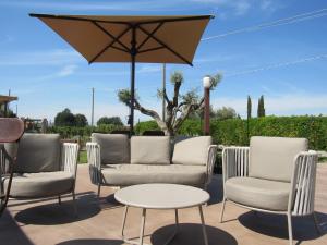a patio with three chairs and a table and an umbrella at Agriturismo Sweet Cottage in Marina di Grosseto