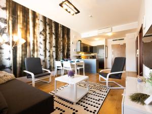 een woonkamer met een bank, stoelen en een tafel bij VacationClub - Olympic Park Apartament B404 in Kołobrzeg