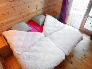 Cama en habitación de madera con sábanas y almohadas blancas en La Rossignolerie - POD Cabanes des châteaux en Chouzy-sur-Cisse