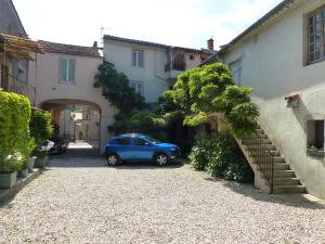 a blue car parked in a driveway between two buildings at Les Glycines in Le Vigan