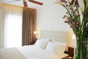 a bedroom with a white bed and a vase of flowers at Armata Boutique Hotel in Spetses