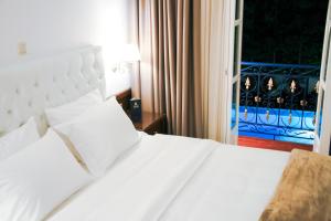 a white bed in a hotel room with a window at Armata Boutique Hotel in Spetses