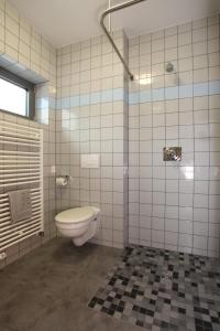 a bathroom with a toilet and a tiled wall at Hotel Alter Zoll in Kleinblittersdorf