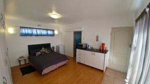 a bedroom with a bed and a kitchen with a microwave at Blouberg Beach Retreat in Bloubergstrand
