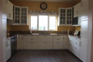 a kitchen with white cabinets and a clock on the wall at The Doc's self catering in Greencastle