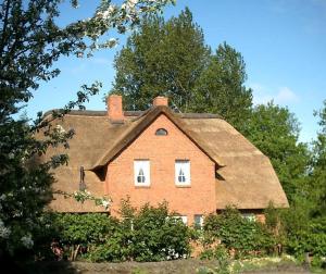 an old brick house with a thatched roof at Haushälfte Luv und Lee in Tating