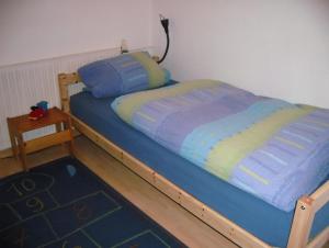 Schlafzimmer mit einem Bett mit blauer Decke und einem Tisch in der Unterkunft Ferienhaus Stecher-Schulz in Sankt Peter-Ording