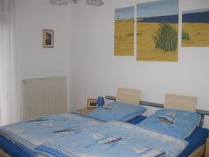 a bedroom with a bed with blue sheets and paintings on the wall at Sonnenoase in Tating