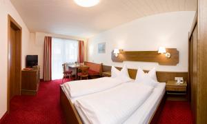 una habitación de hotel con una cama grande y una mesa en Hotel Edelweiss, en Pfunds
