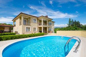 a villa with a swimming pool in front of a house at Apartments Sime in Matulji