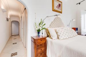 1 dormitorio con cama blanca y tocador de madera en Torre Silja en Positano