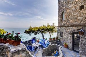 a stone building with a table and chairs and the ocean at Torre Silja in Positano