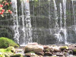 a waterfall with rocks in front of a waterfall at Cathedral View - Swn yr Afon in Brecon