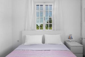 a white bedroom with a bed and a window at Vourvourou Villa Mare Verde by Luxlikehome in Vourvourou