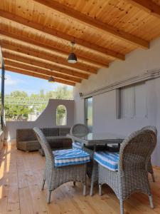 a patio with wicker furniture and a wooden ceiling at Varkiza's Cottages in Varkiza