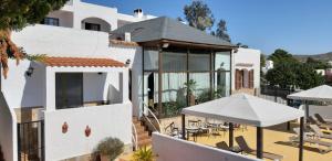 a white house with a patio with tables and umbrellas at Family Agua Amarga in Agua Amarga