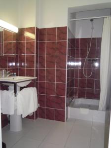 La salle de bains est pourvue d'un lavabo et d'une douche avec du carrelage rouge. dans l'établissement Hôtel Cuulong, à Labarthe-Inard