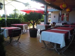 a restaurant with tables and chairs and an umbrella at Hôtel Cuulong in Labarthe-Inard