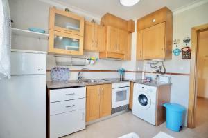 a kitchen with wooden cabinets and a washer and dryer at The Wavecatcher - Deluxe Flat - Baleal / Peniche in Ferrel