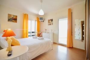 a bedroom with a white bed and a table with a lamp at The Wavecatcher - Deluxe Flat - Baleal / Peniche in Ferrel