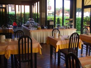 a restaurant with tables and chairs with yellow table cloth at Hotel Derby in Sirmione