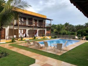 a resort with a pool and chairs and a building at Villa Aurora in Flecheiras