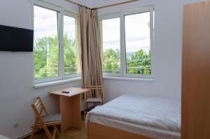 a bedroom with a bed and a desk and windows at Casa Rezidentiala Pasteur in Cluj-Napoca