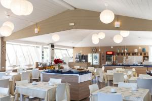 a restaurant with white tables and white chairs and lights at Hotel Baia Del Sole in Marina di Ragusa