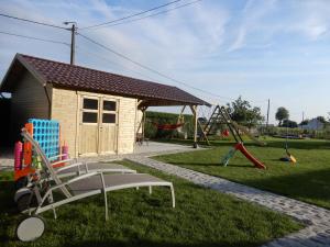 um pequeno edifício com um parque infantil com baloiços em Holiday Home Cuylehoeve em Leffinge