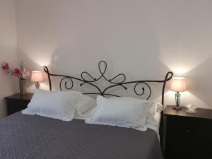 a bedroom with a bed with white pillows and two lamps at Apartments Jerko in Primošten