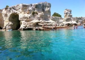 a group of people in the water next to a cliff at Villetta Carati in Torre dell'Orso